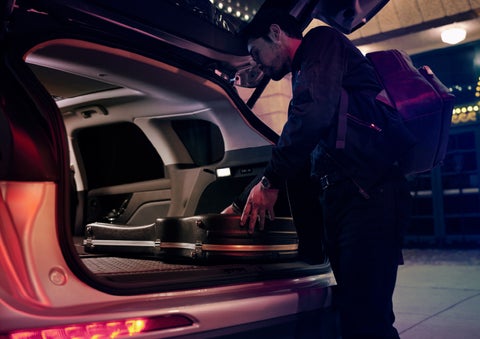 A musician slides his guitar case into the cargo space of a 2022 Lincoln Corsair with the rear seats folded flat to provide ample cargo space | Fair Oaks Lincoln in Naperville IL